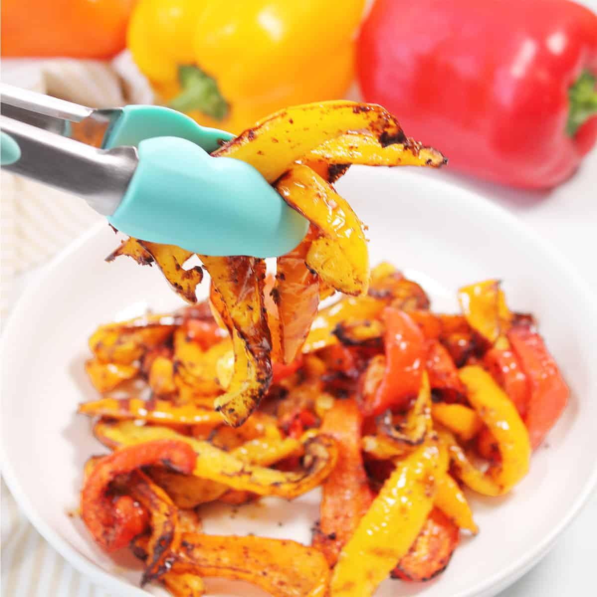 Holding Air Fryer Peppers with tongs.