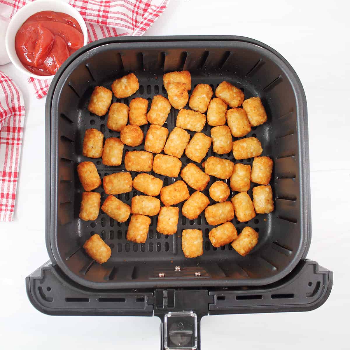 Air fried tater tots in air fryer basket.