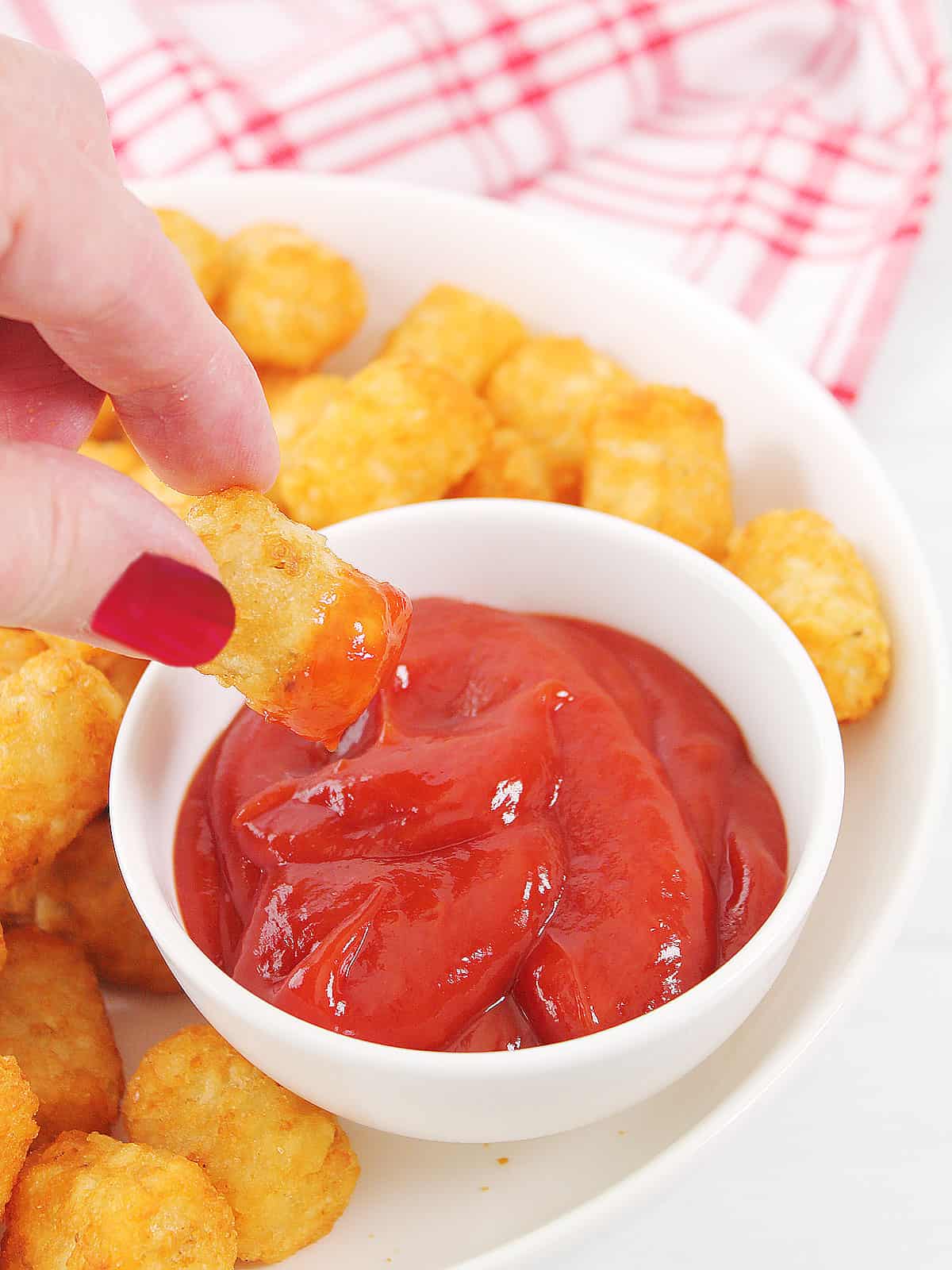 Dipping tater tot into ketchup.