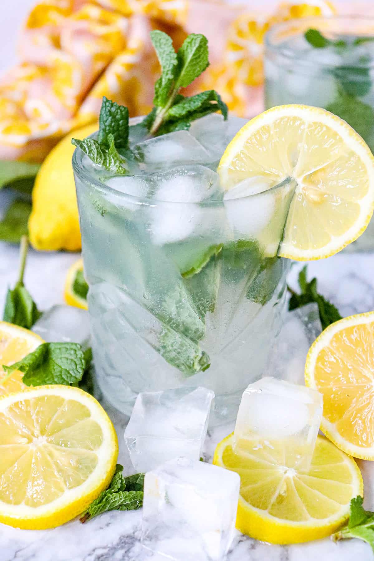 Non-alcoholic lemon mojito surrounded with lemons and ice.