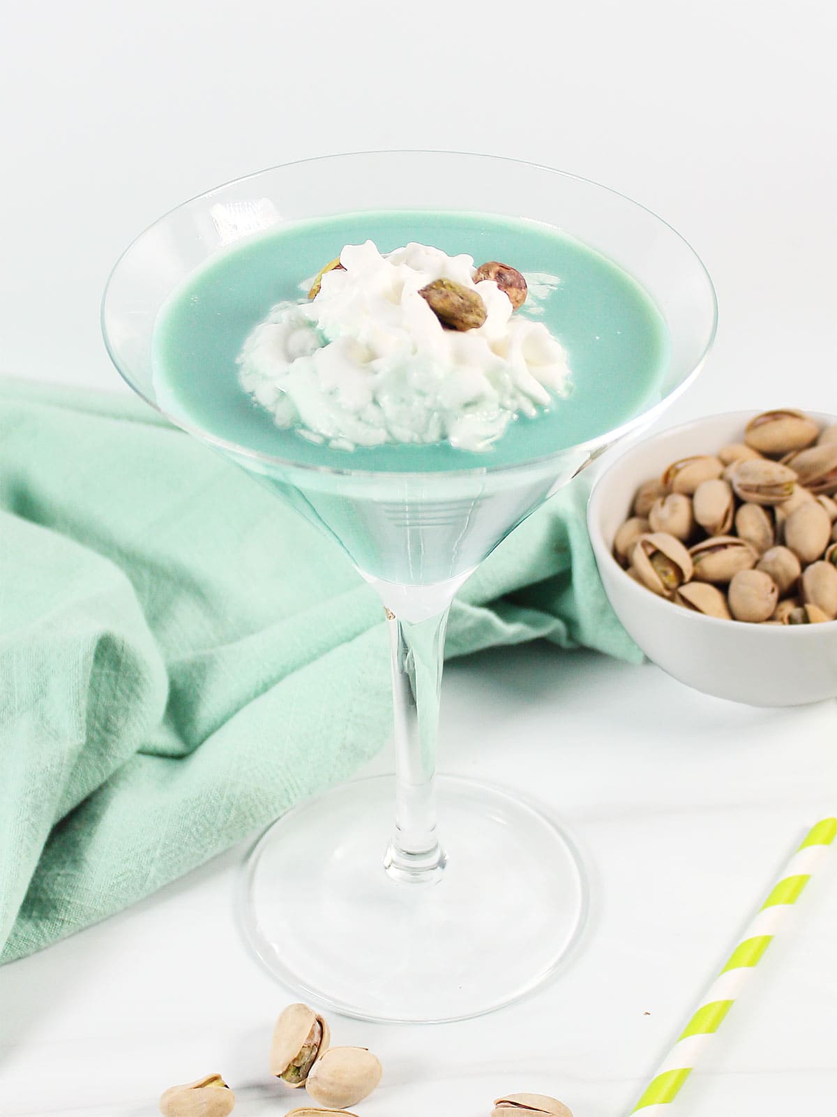 Pistachio Martini garnished with whipped cream and three pistachios.