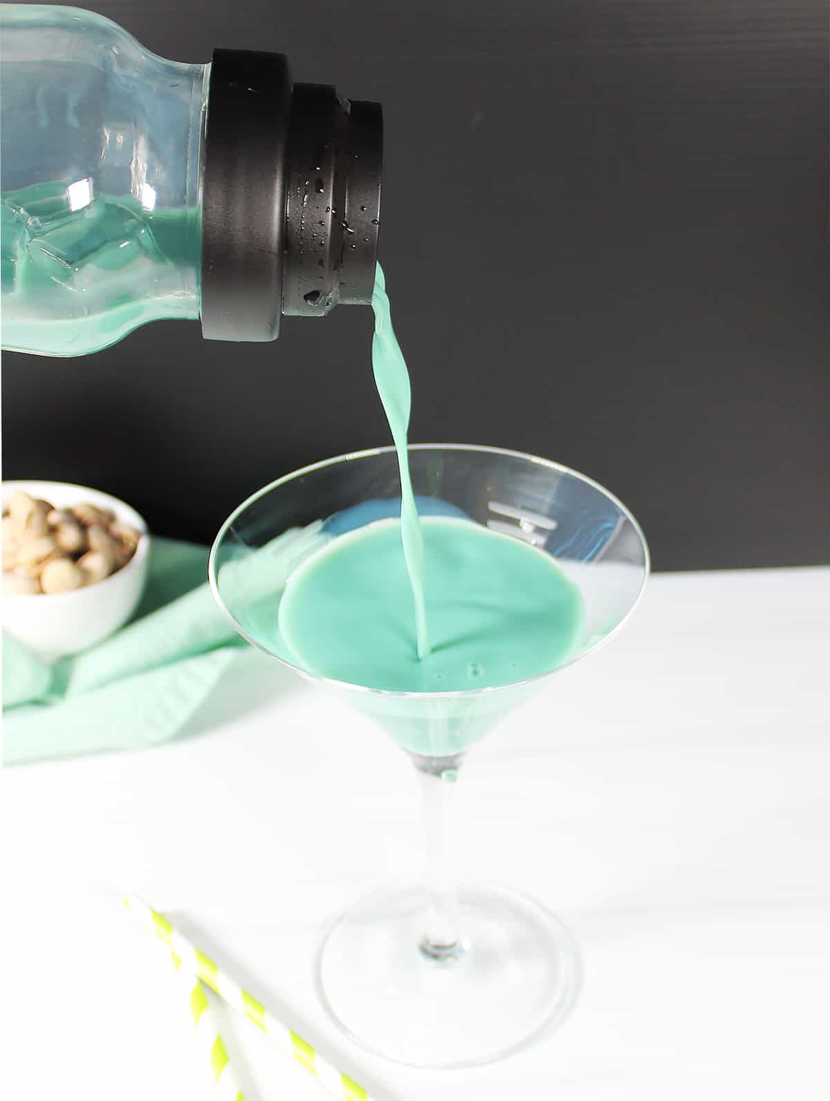 Pouring pistachio martini into martini glass.