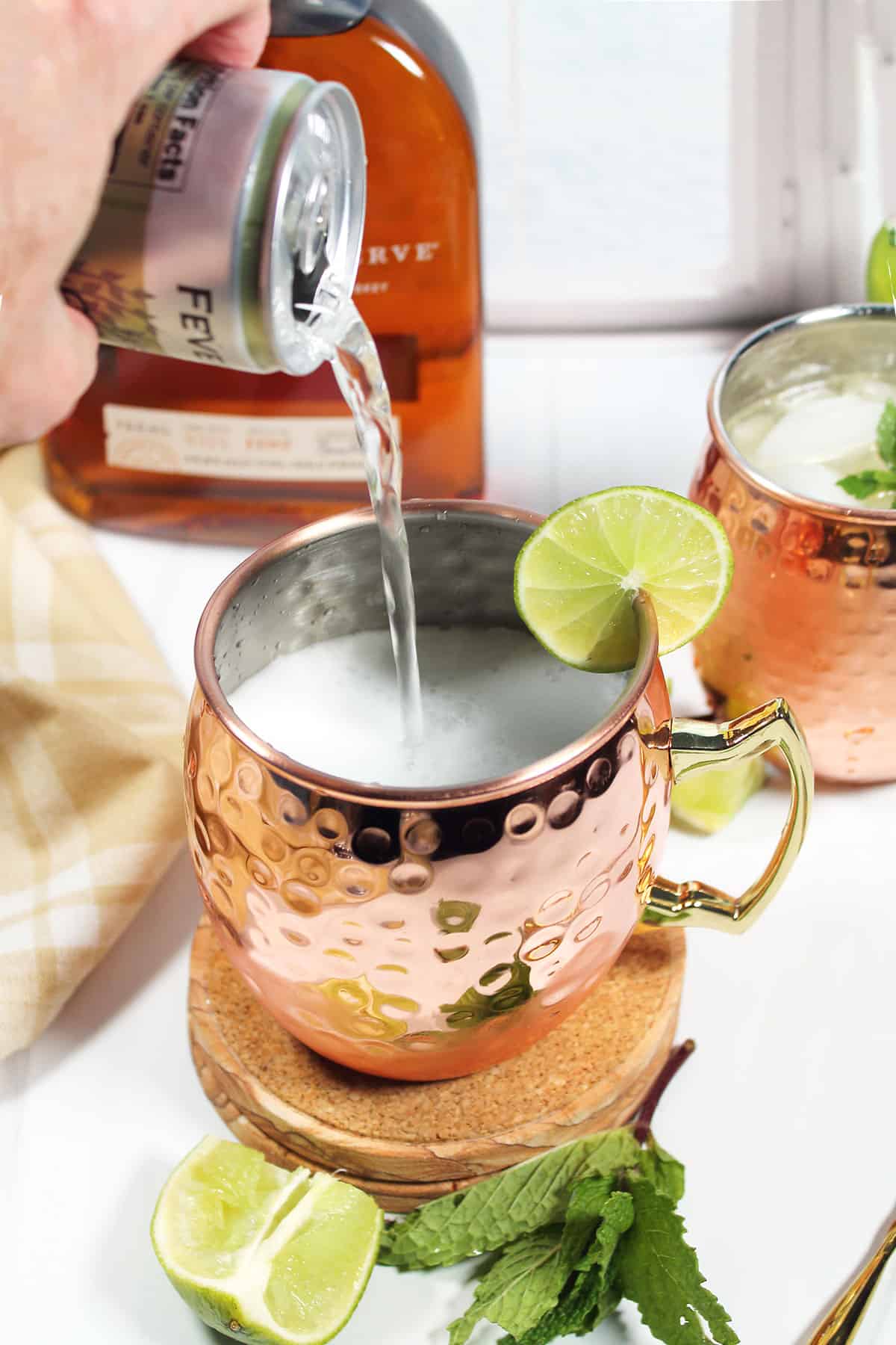 Pouring ginger beer into copper mug.