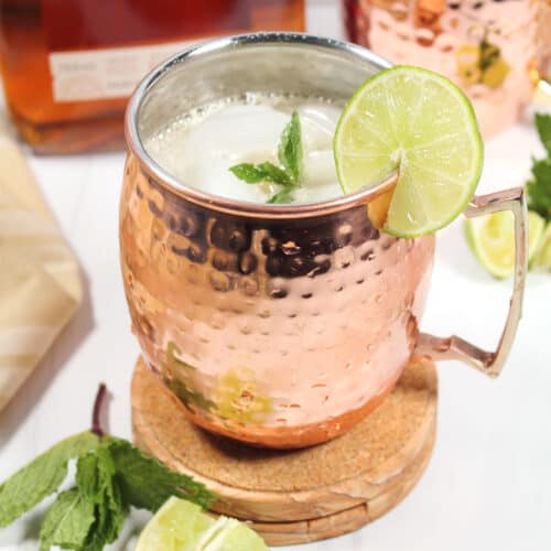 Bourbon Mule in copper mug with garnishes.