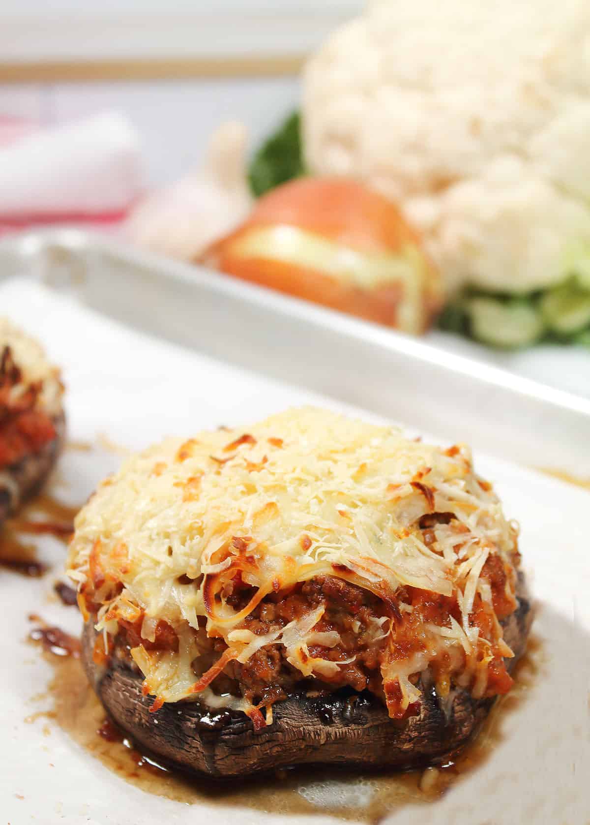 Ground beef stuffed portobello mushrooms on baking sheet.