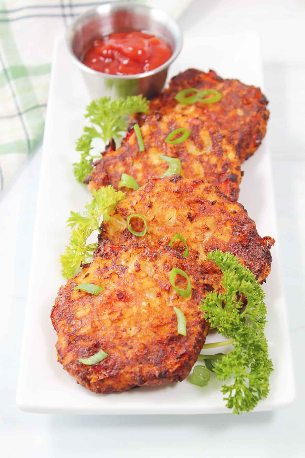 Easy cauliflower hash browns on platter with green onions and parsley.