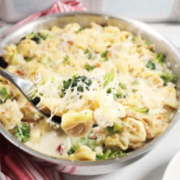 Scoop of tortellini alfredo on serving spoon.