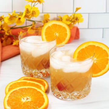 Two Amaretto Sour cocktails with orange garnish.