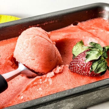 Scooping creamy strawberry lemonade sorbet out of pan.