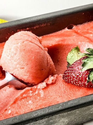 Scooping creamy strawberry lemonade sorbet out of pan.