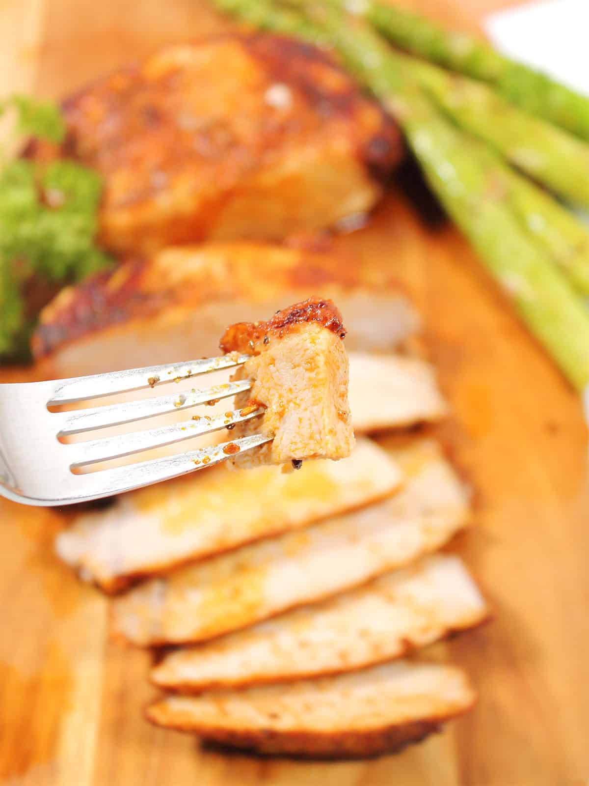 Bite of pork chop on fork over sliced air fried chops with gravy.