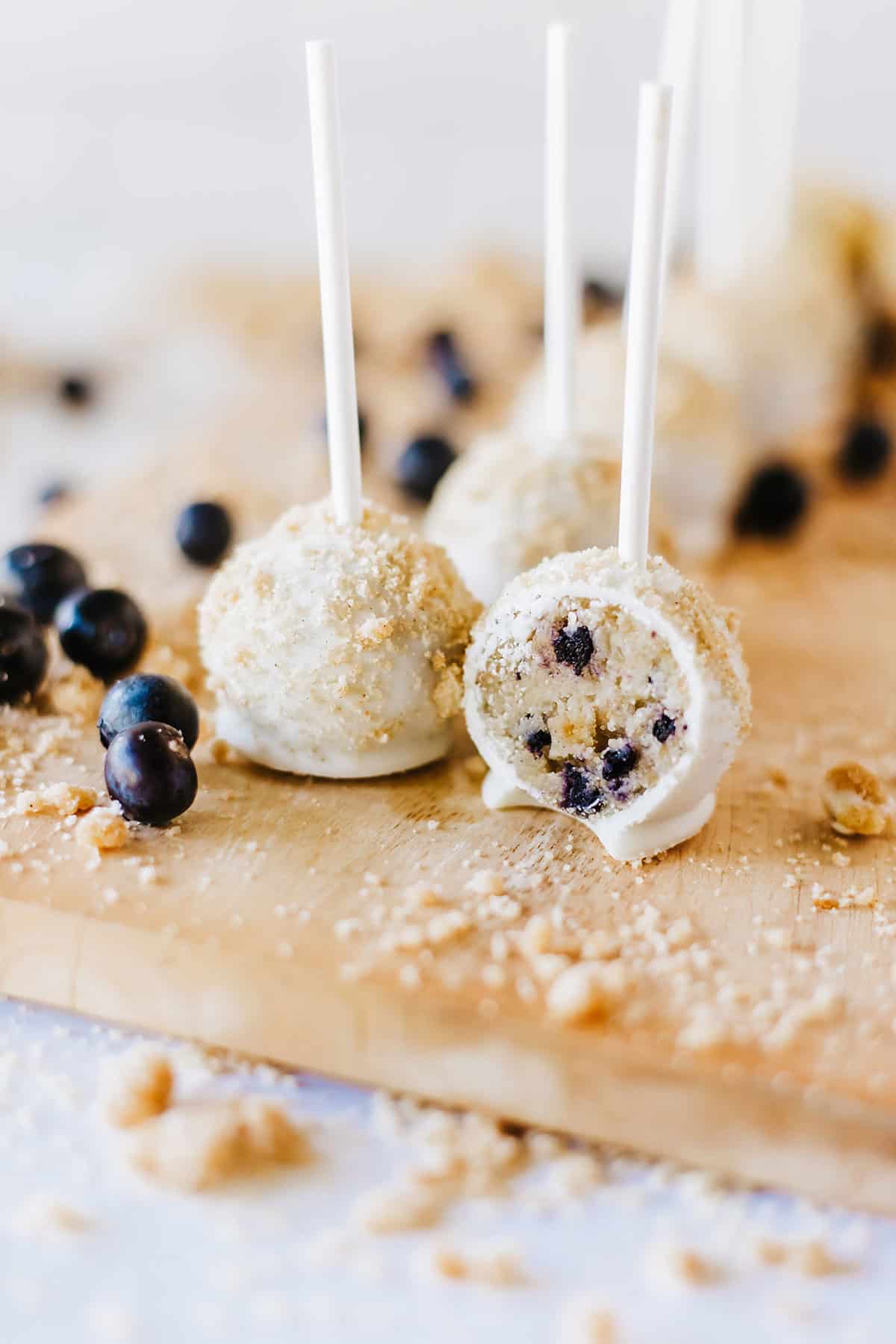 Blueberry Muffin Cake Pops on cutting board with one halved.