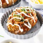 Single baked potato in ramekin filled with pulled pork.