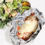 Air fried chicken in foil plated with salad.