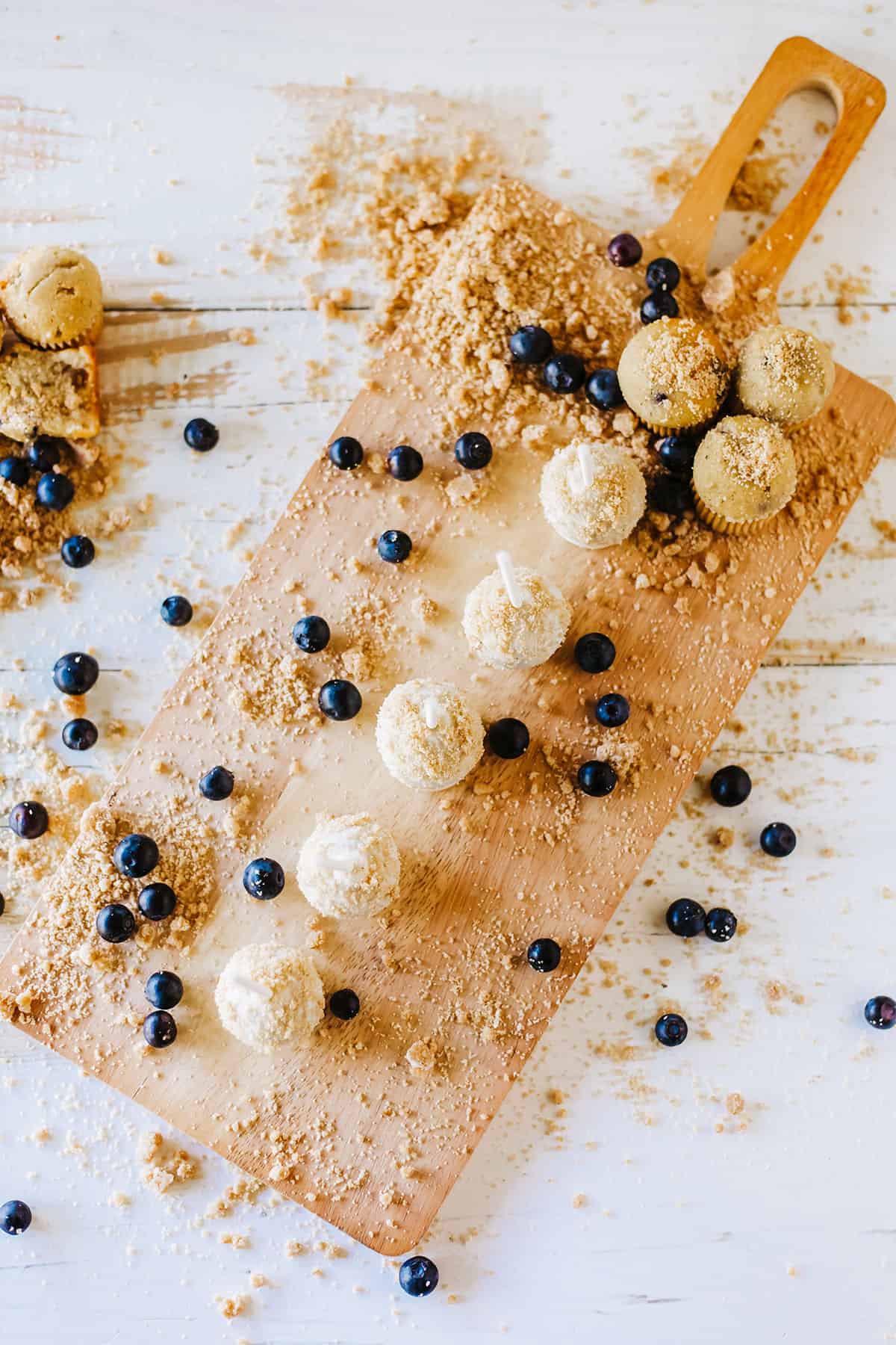Overhead of blueberry cake pops on wooden board with blueberries.