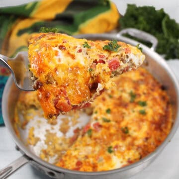 Lifting slice of frittata with chorizo from skillet.