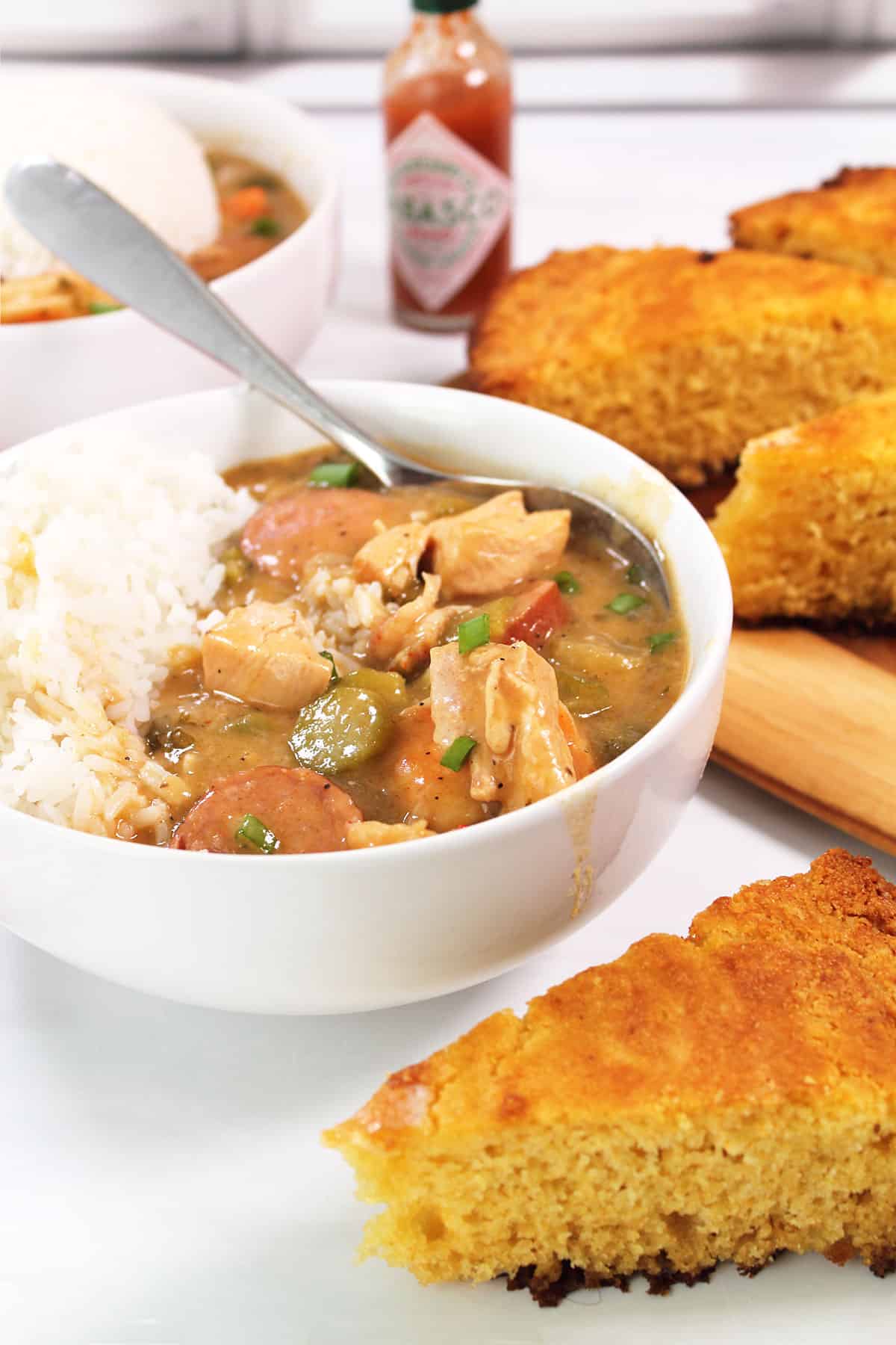 Two bowls of Chicken sausage and shrimp gumbo with rice and cornbread.