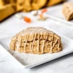 Plated pumpkin scone with glaze and drizzle.