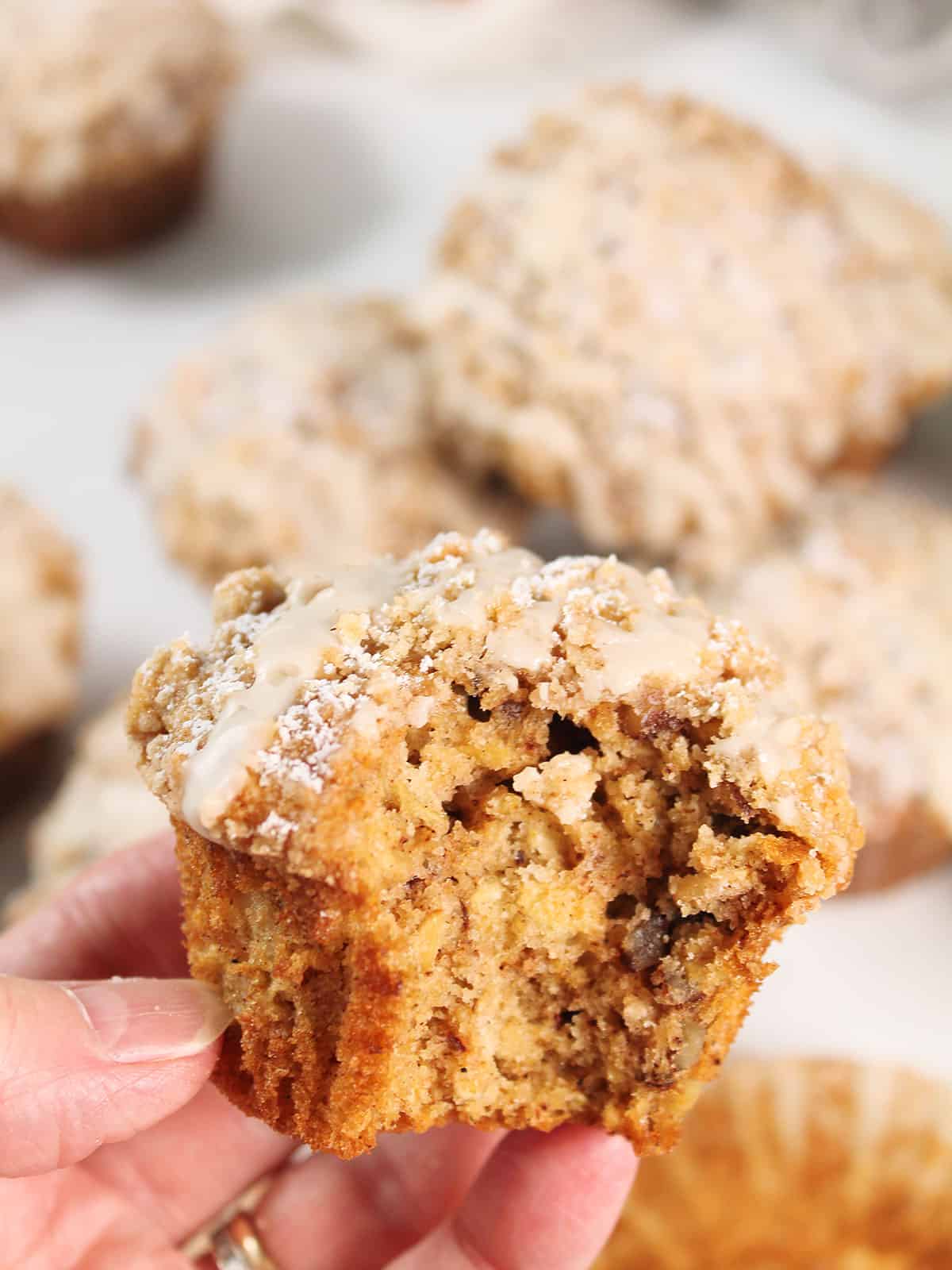 Holding a maple oatmeal muffin with bite out.