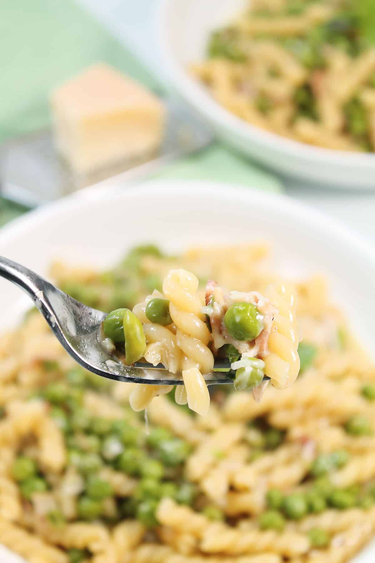 Forkful of pasta e Piselli over serving bowl.