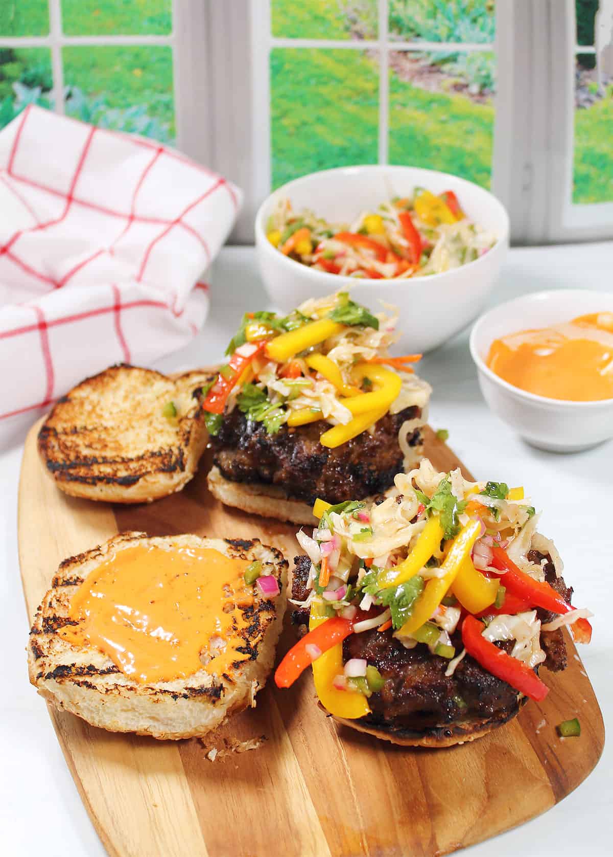 Bulgogi Burgers topped with crispy slaw on wooden board.