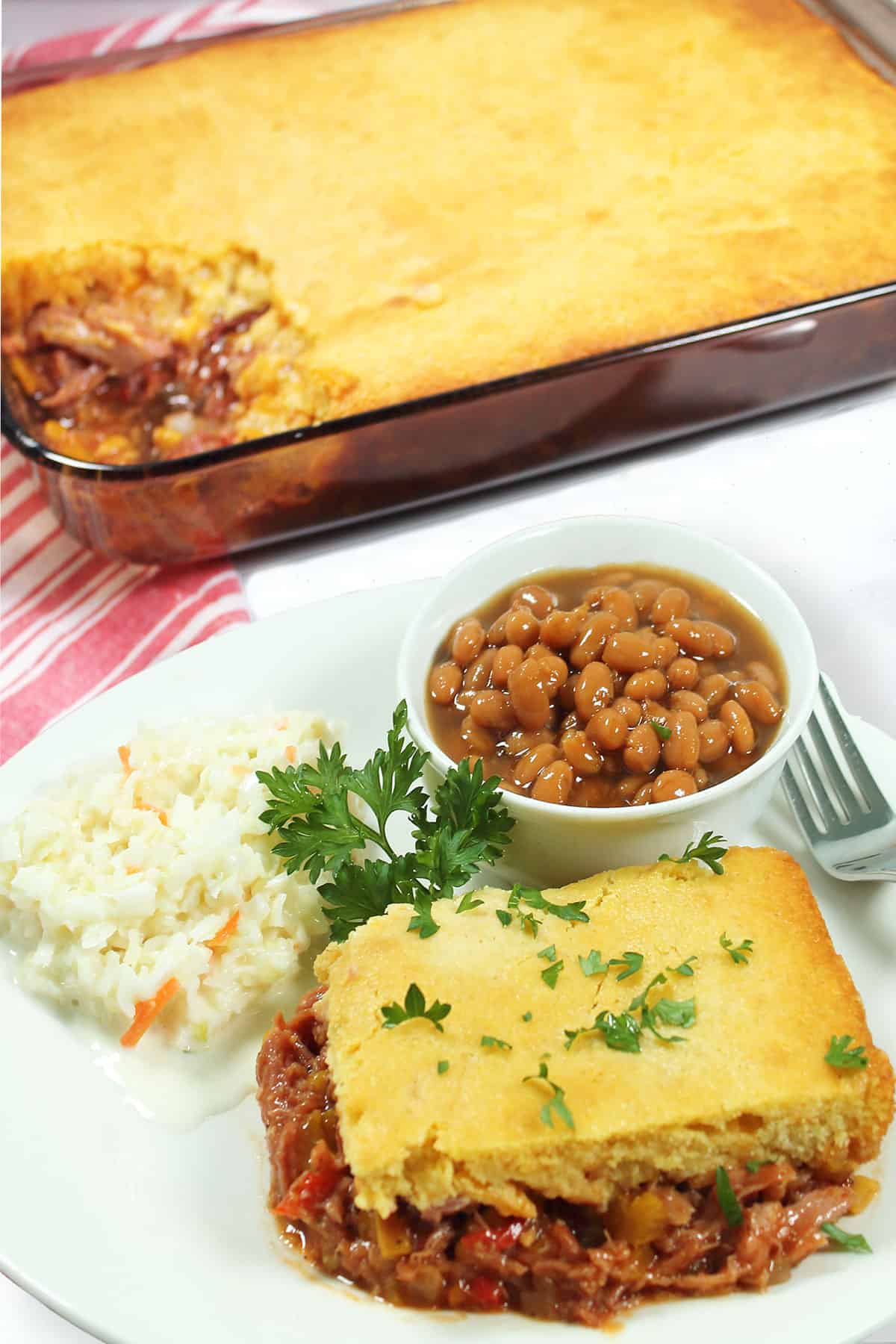 Plated serving of BBQ Pulled Pork Casserole in front of casserole dish.