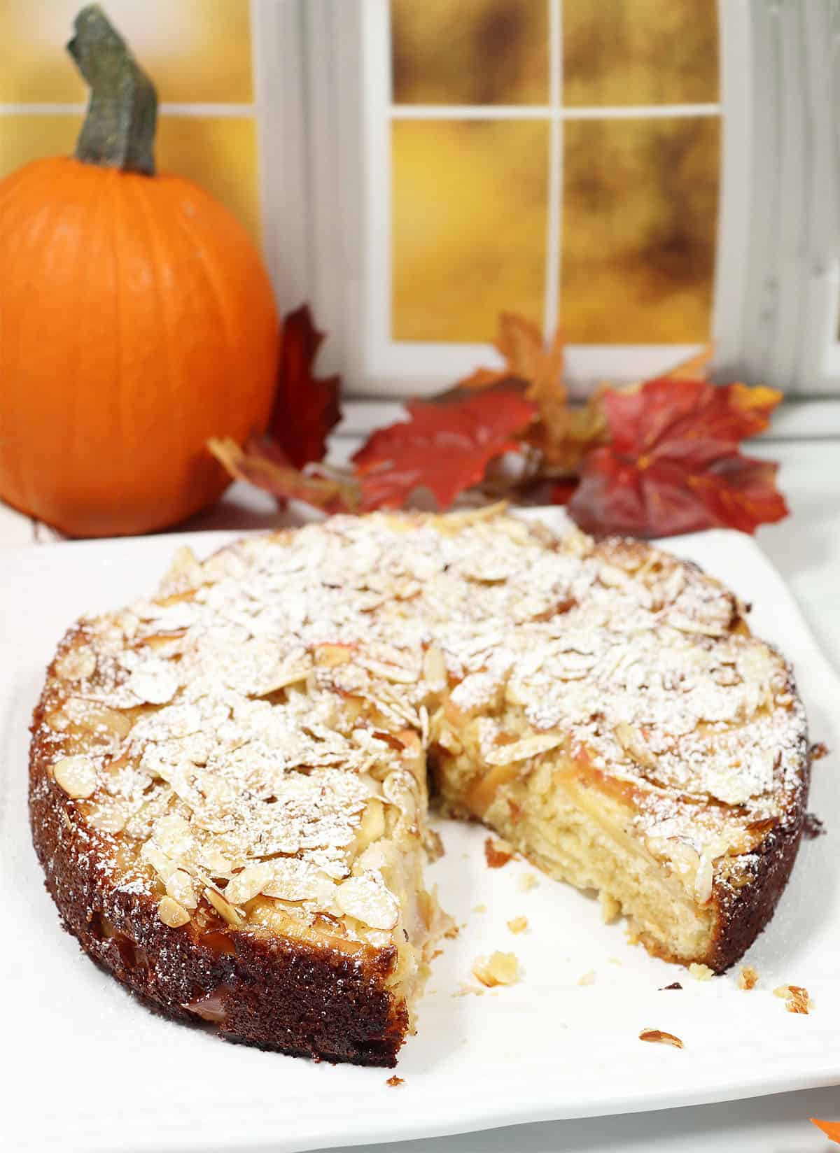 Apple Almond Cake with slice out on white platter.