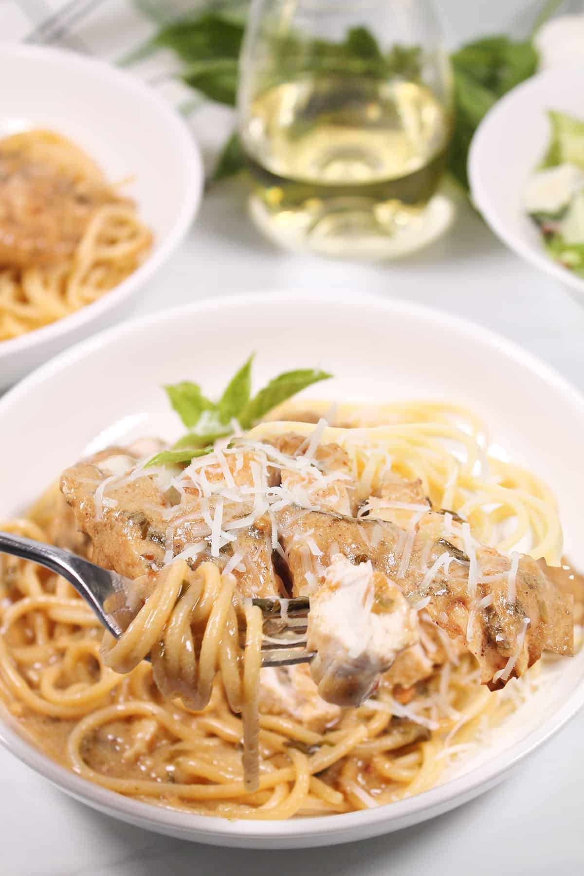 Bite of creamy basil chicken on fork.