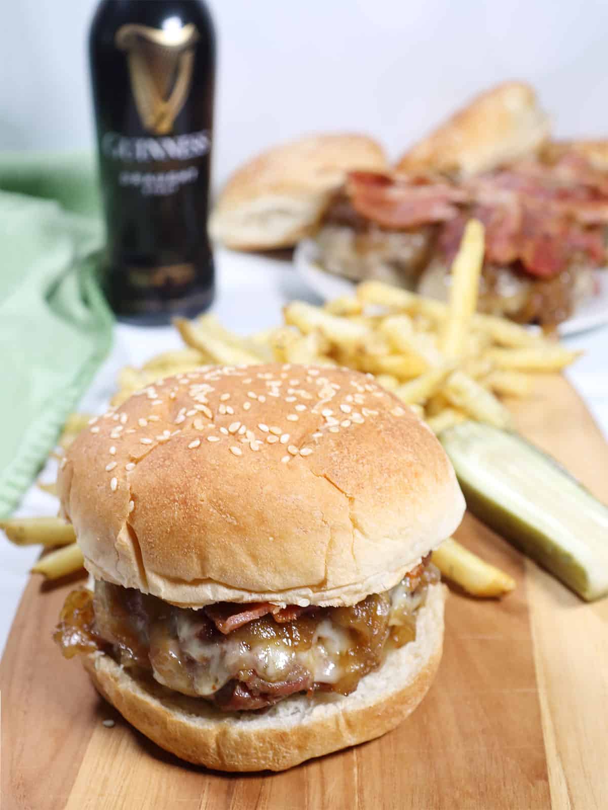 Corned Beef Burger with caramelized onions, cheese, and bacon on a roll with fries.