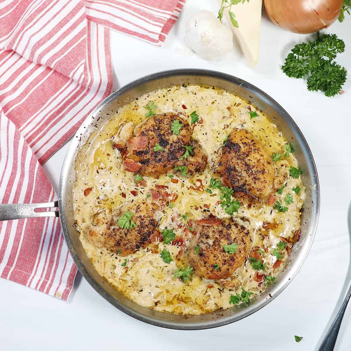 Garnished garlic chicken thighs in skillet.