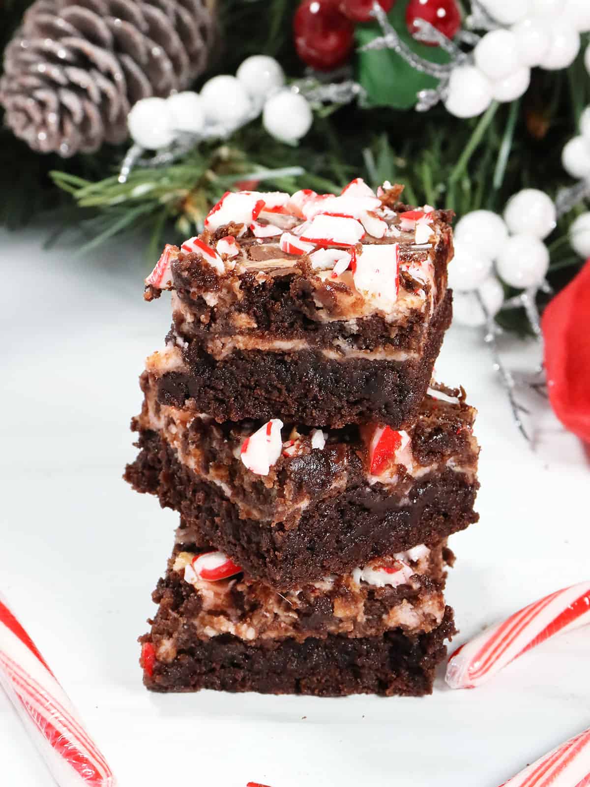 Peppermint Candy Cane Swirl Brownies stacked with candy canes.