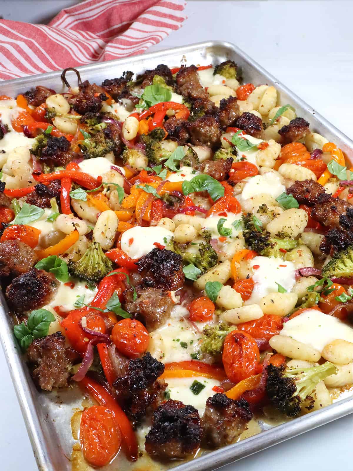 Closeup of gnocchi, sausage and vegetables on sheet pan.