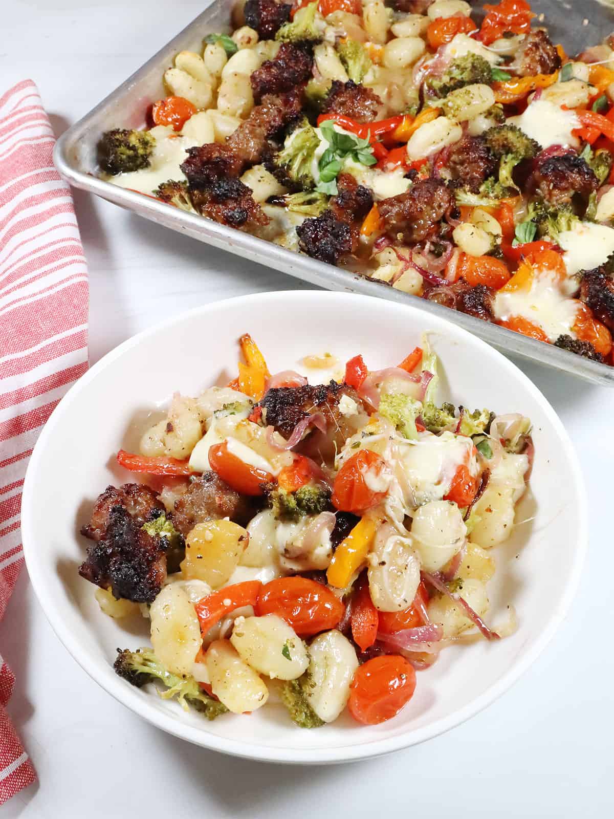 Sheet Pan Gnocchi with sausage serving in bowl with pan in back.