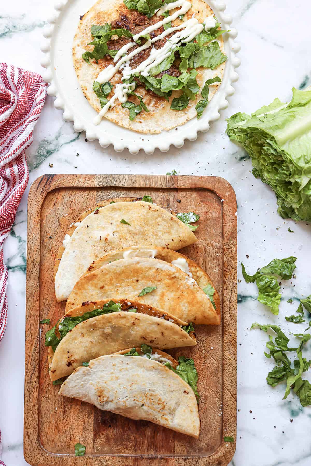 Caesar Salad Smash Tacos on board with open faced one in back.