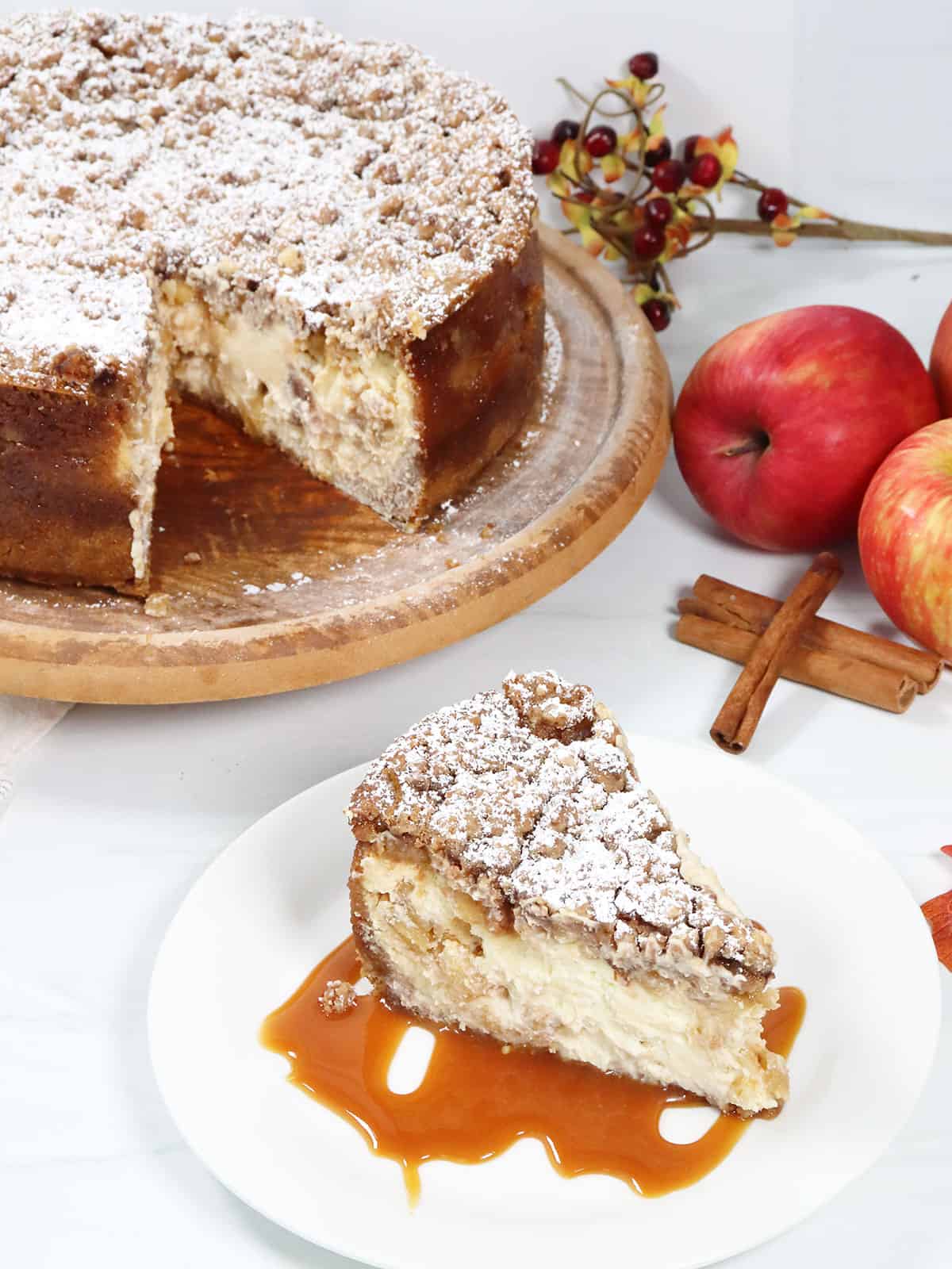 Caramel Apple  Crumble Cheesecake slice with cake behind it.