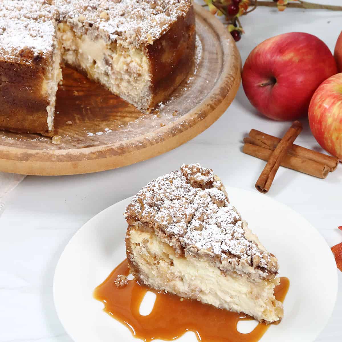 Plated slice of Caramel Apple Crumble Cheesecake by whole cake.