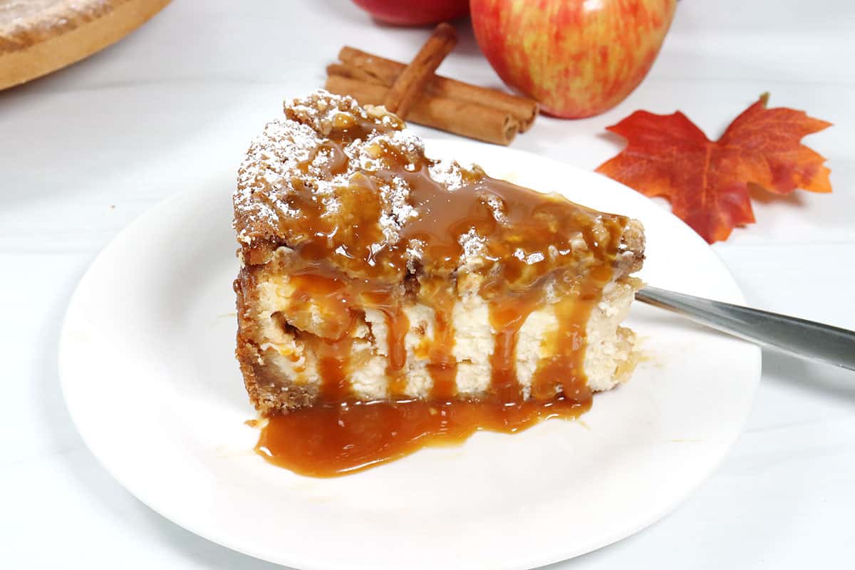 Slice of apple crumble cheesecake drizzled with caramel.