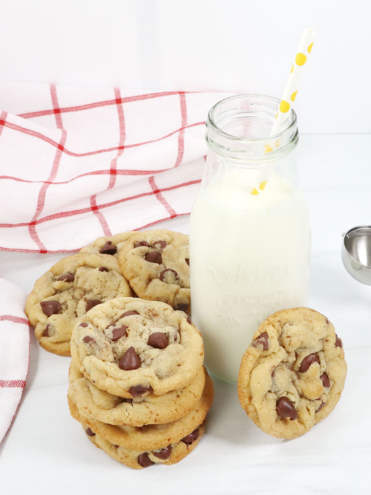 Stacked soft chocolate chip cookies around milk bottle.