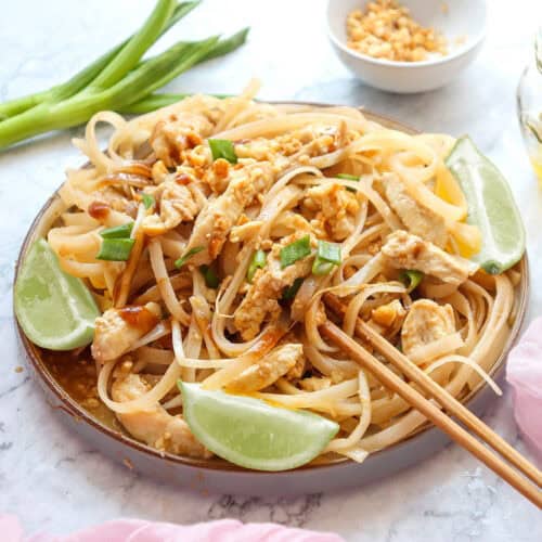 Chicken Pad Thai in serving bowl with lime wedges.