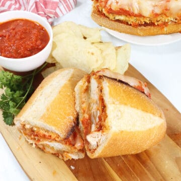 Halved Chicken Parmesan Sub on cutting board.