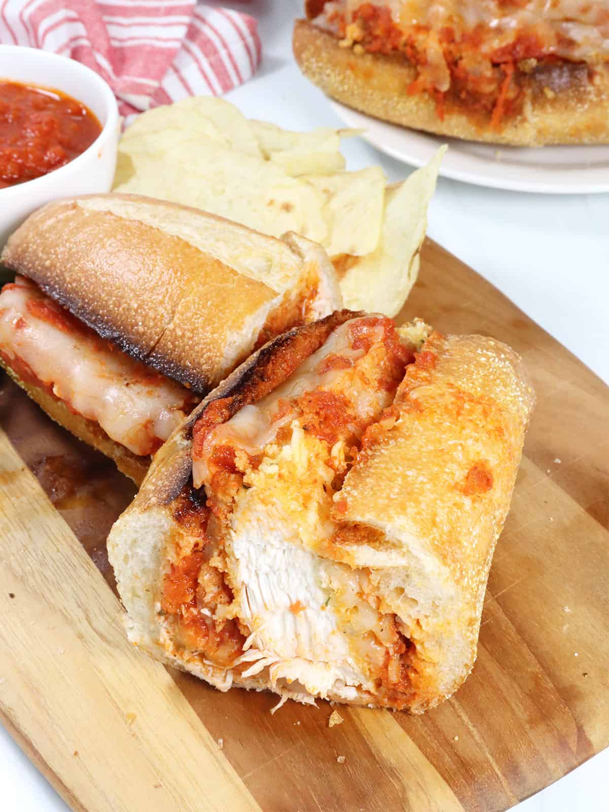 Halved Chicken Parmesan Sub with chips.