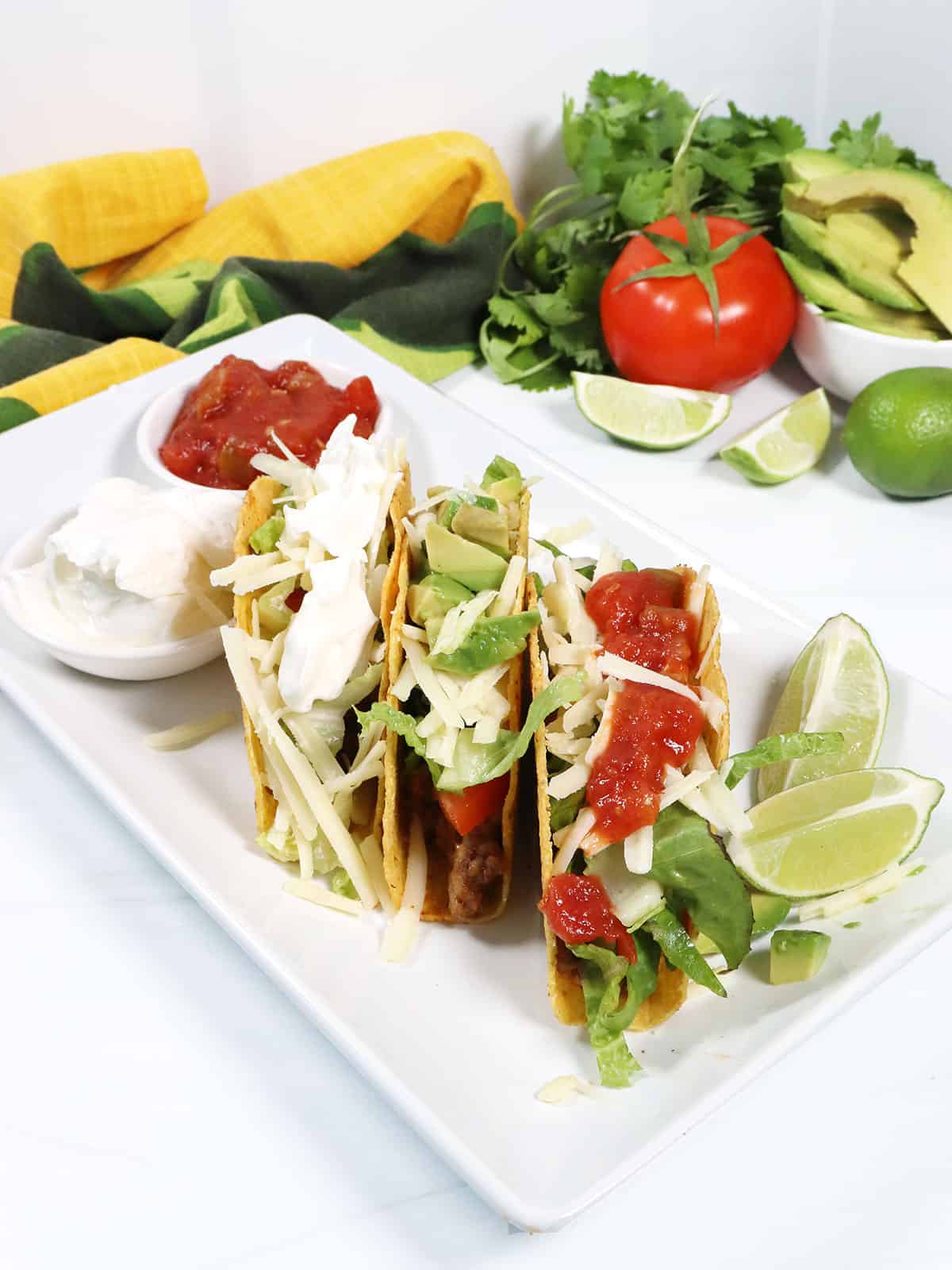 3 Ground Beef Tacos standing on platter with garnishes.