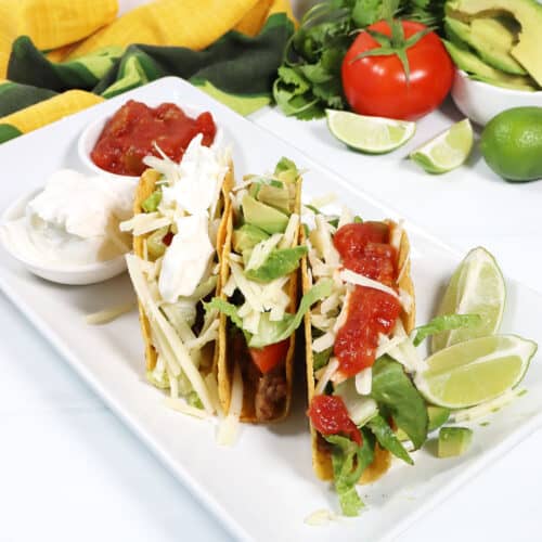 Easy Ground Beef Tacos on platter with garnishes.