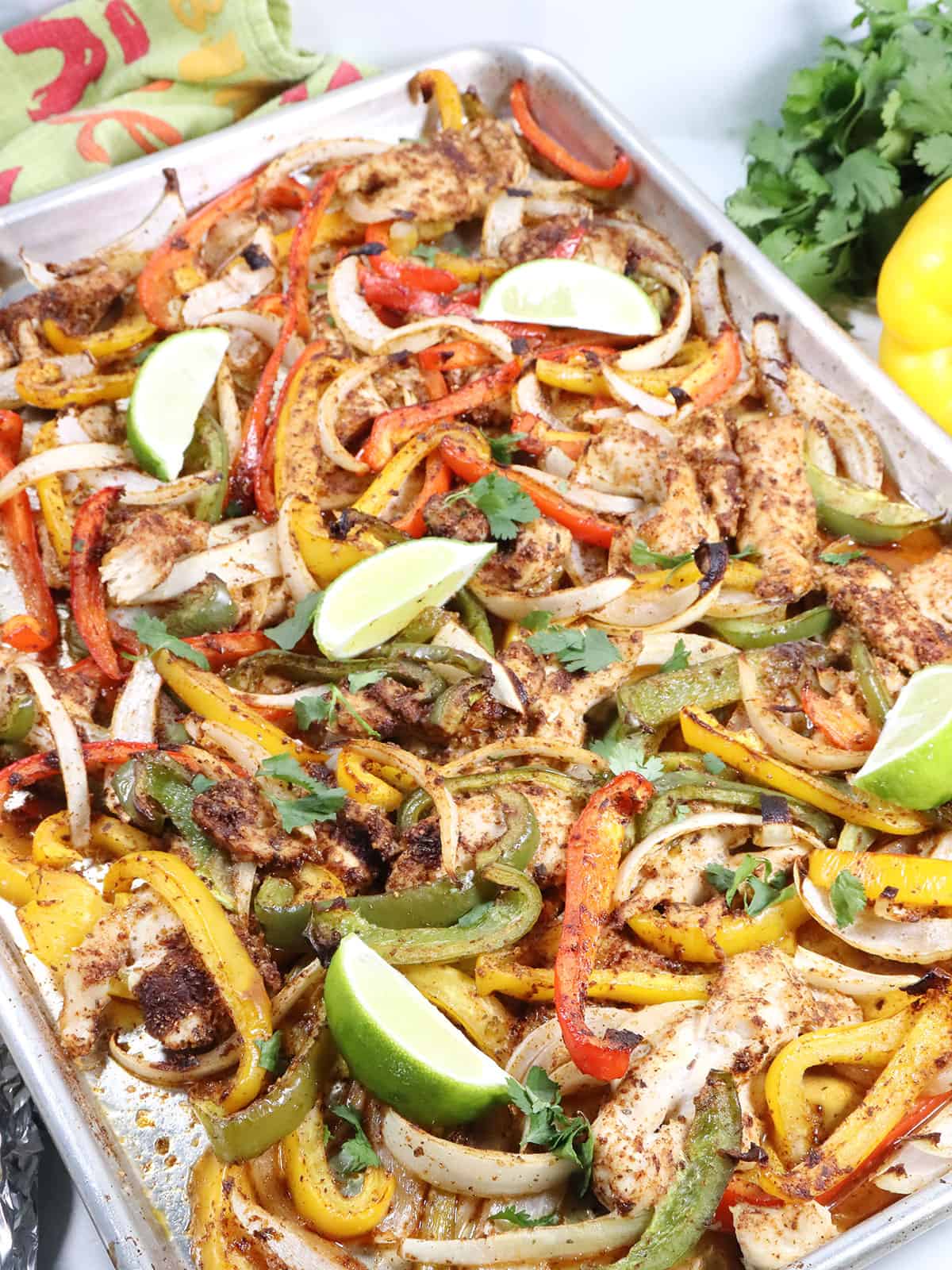 Roasted fajitas dinner on sheet pan with limes.